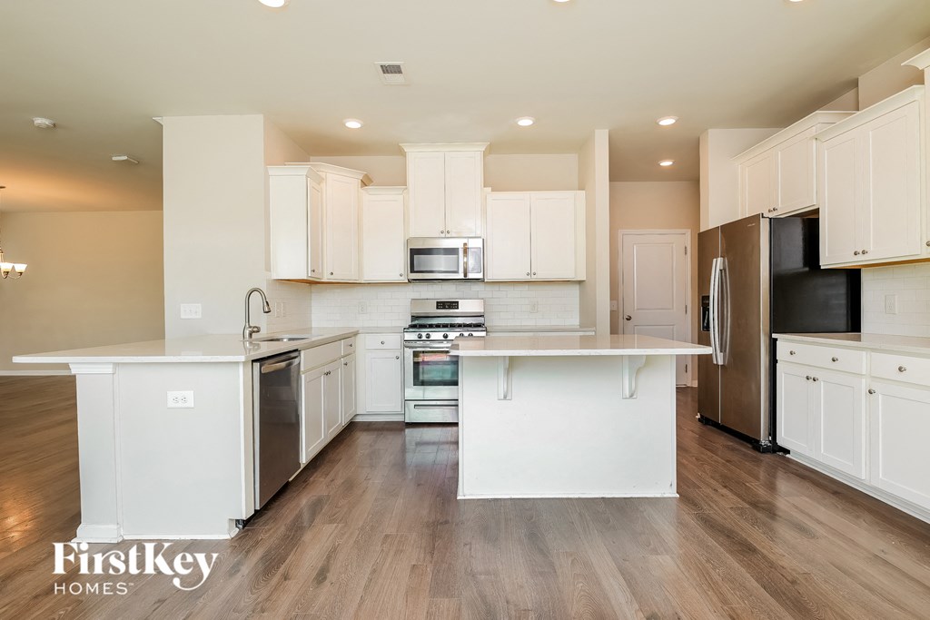 a large kitchen with white cabinets and stainless steel appliances