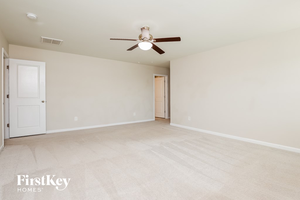 a spacious living room with white walls and a ceiling fan