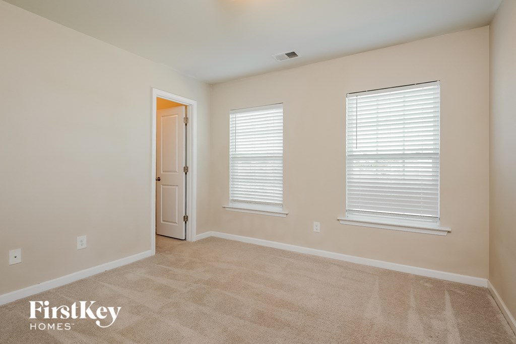 a spacious living room with two windows and a door