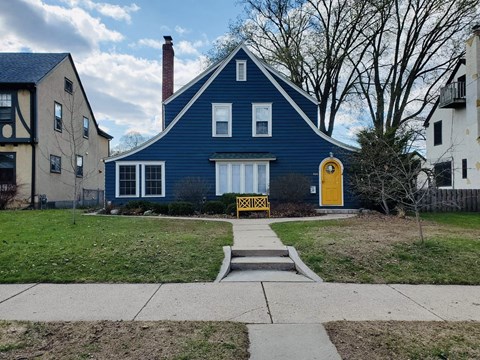 a blue house with a yellow door and a sidewalk