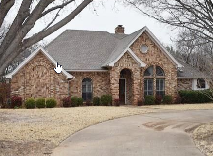 a brick house with a driveway and a tree