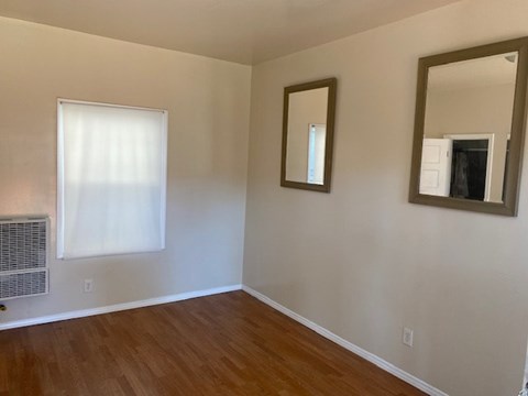 A room with a window, a mirror, and a picture frame on the wall.