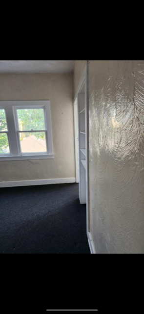 A room with a window and a carpeted floor.
