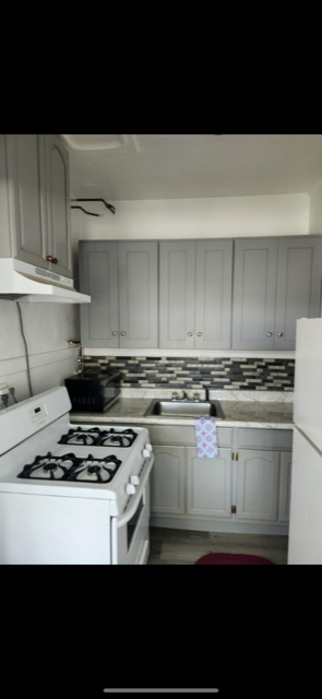 A kitchen with a white stove and cabinets.