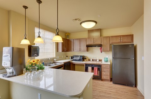 A kitchen with a white counter top and a black refrigerator.