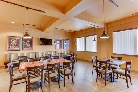 A dining room with a table surrounded by chairs.