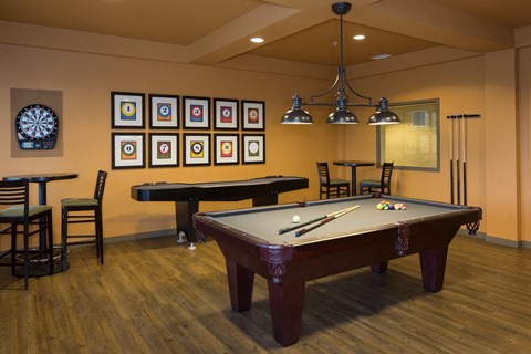 A pool table with a dart board on the wall.