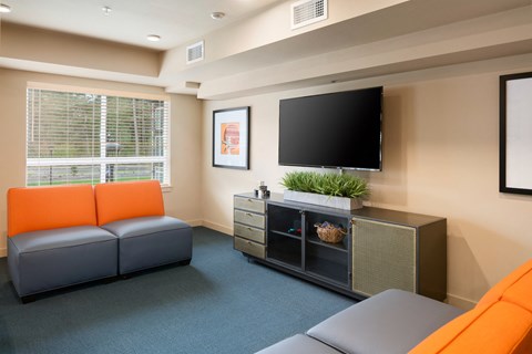A living room with orange couches and a grey sofa.
