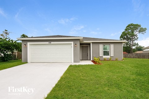A two-car garage with a white door is situated in a grassy area.