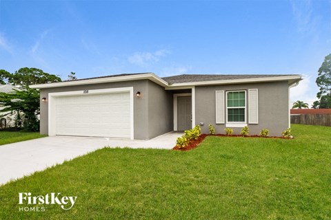 A house with a garage and a driveway in front of it.