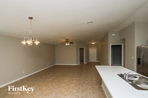 A kitchen with a sink and a fridge in a room with tiled flooring.
