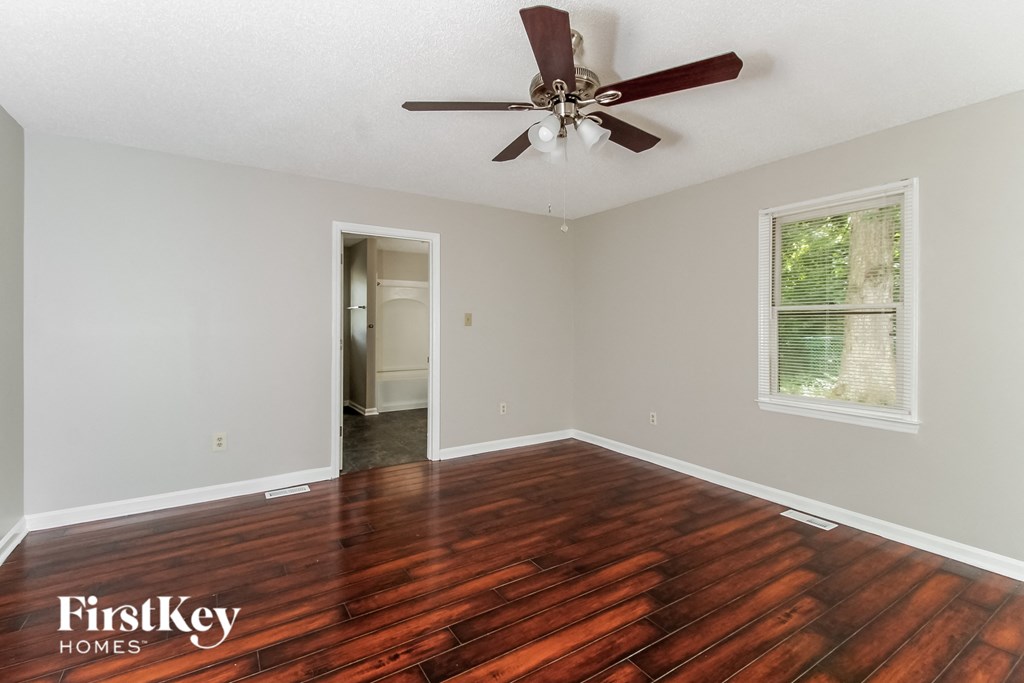 A room with a ceiling fan and wooden flooring.