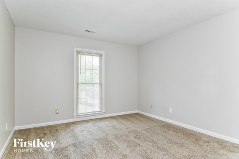 a spacious living room with carpet and a window