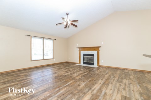 A spacious room with a fireplace and a ceiling fan.
