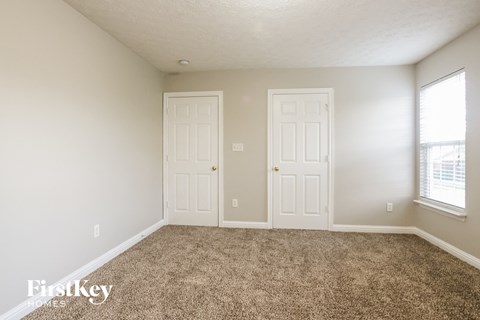 a carpeted living room with two doors and a window