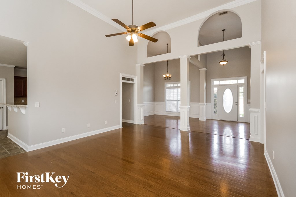 an empty living room with wood floors and a ceiling fan