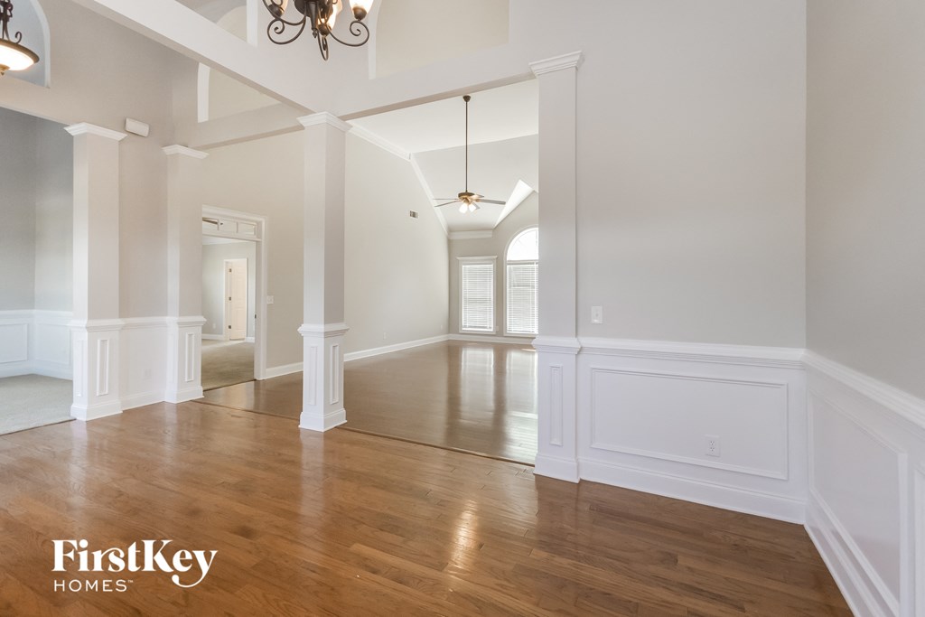 an empty living room and dining room with white pillars and wood floors