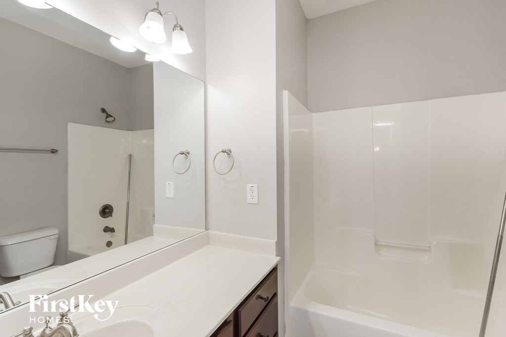 a white bathroom with a large mirror and a tub and sink