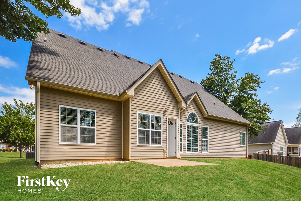 side view of a tan house with white doors and a green lawn