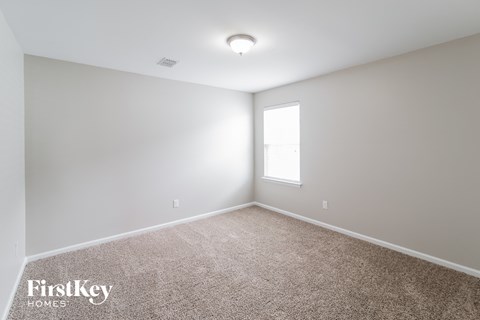 a spacious room with carpet and a window