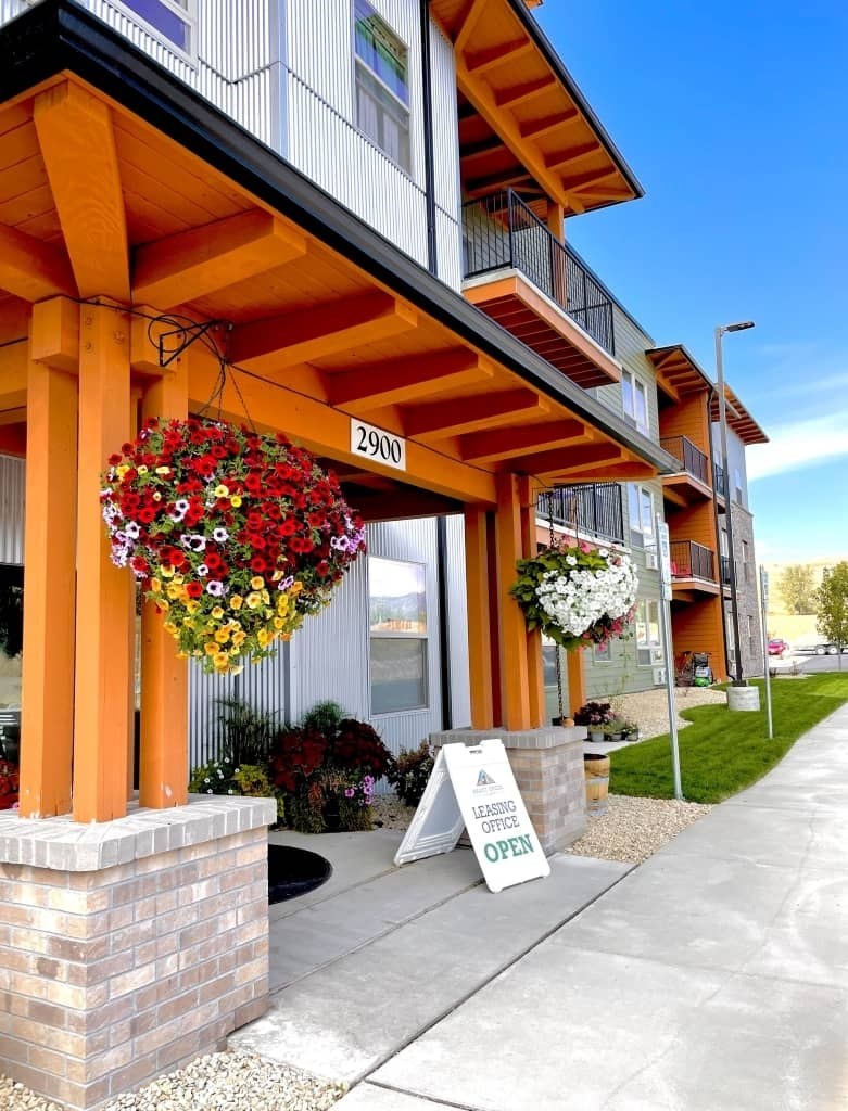 A building with a sign that says "Leasing Office Open" in front of it.
