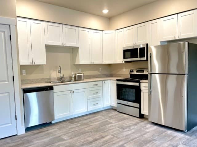 A kitchen with white cabinets and stainless steel appliances.