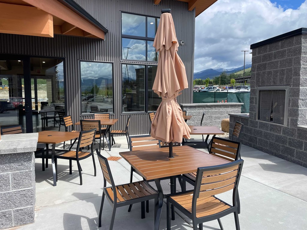 A patio with wooden chairs and tables is set up outside a building.
