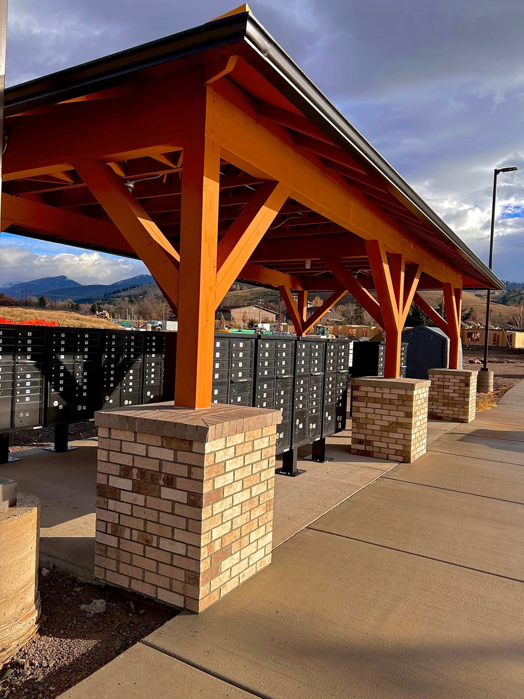 A covered walkway with orange pillars and a brick pillar in the foreground.