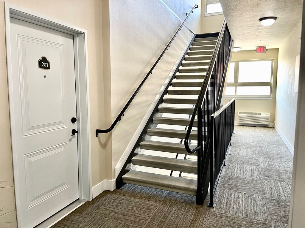 A staircase with a black railing and a white door with the number 201 on it.