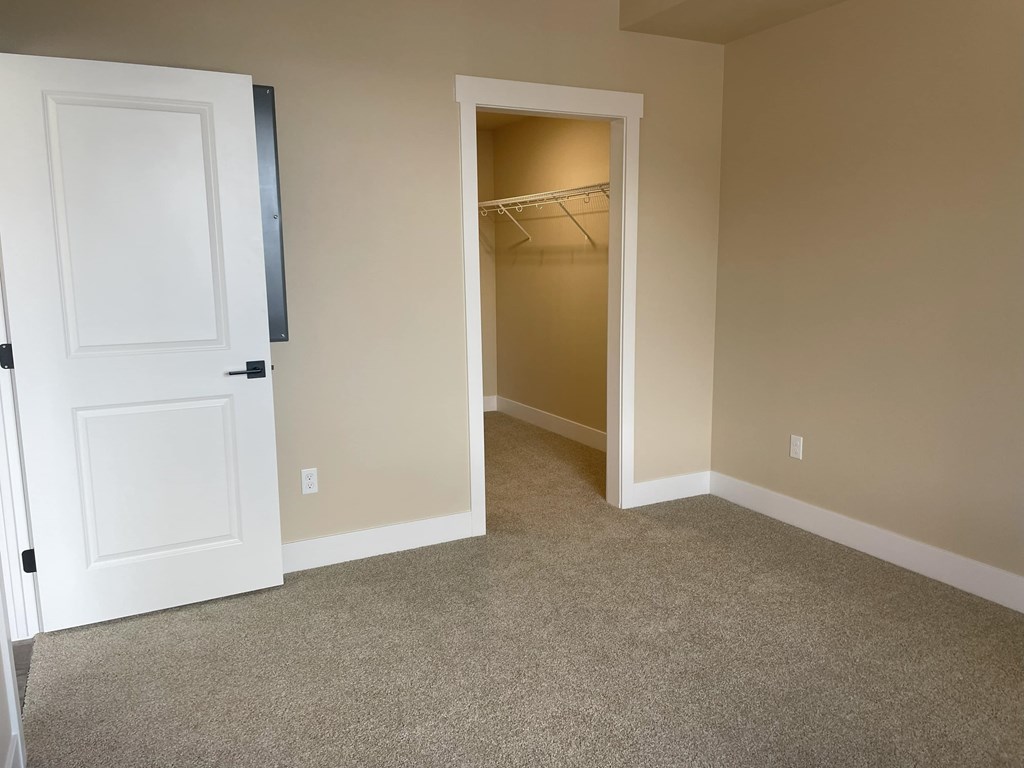 A room with a white door and a carpeted floor.