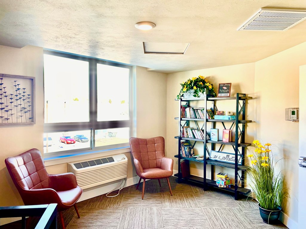A room with a red chair, a brown chair, and a bookshelf.