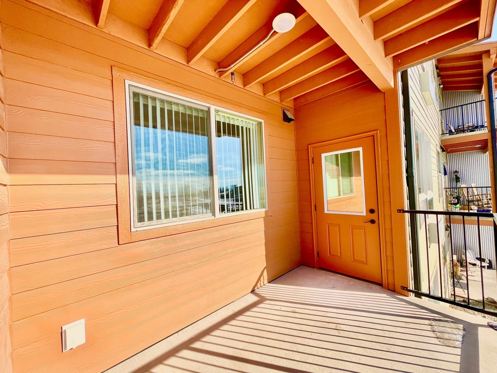 A wooden deck with a door and a balcony.