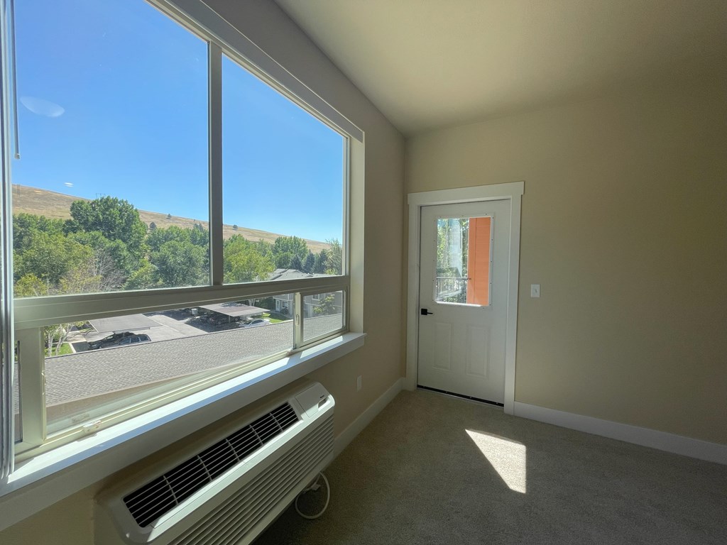 A room with a window overlooking a parking lot.