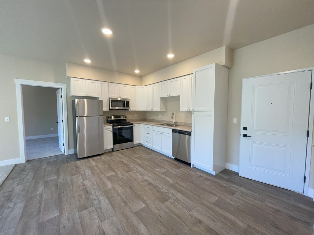 A kitchen with white cabinets and a wooden floor.