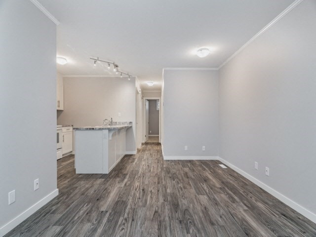 the living room and kitchen of an apartment with wood flooring