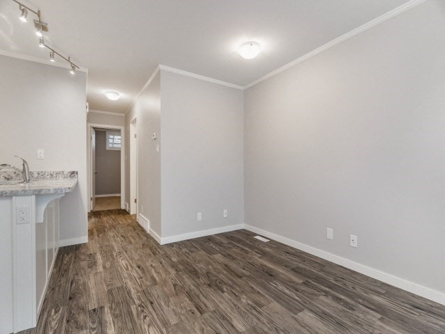 the living room and kitchen of an empty house with wood flooring