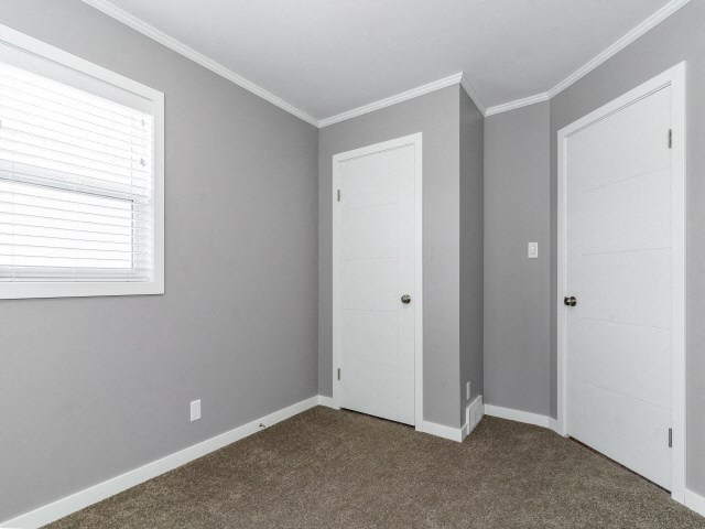 an empty bedroom with two doors and a window