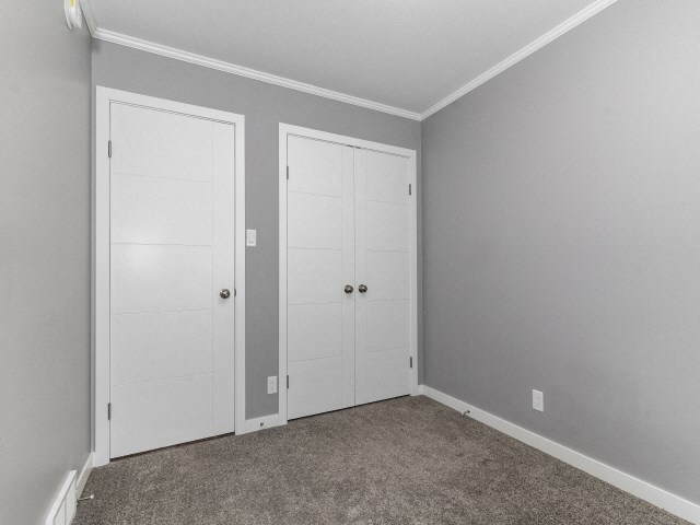 an empty room with two white doors and a carpet