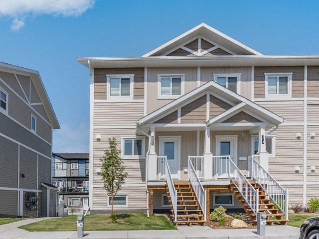 a tan house with stairs in front of a sidewalk