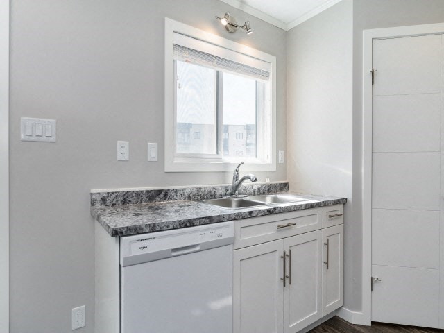a white kitchen with granite counter tops and a window