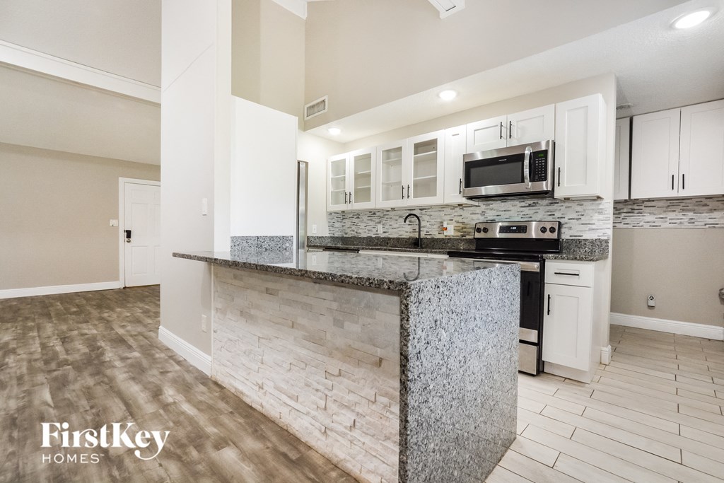 a kitchen with white cabinets and a granite counter top