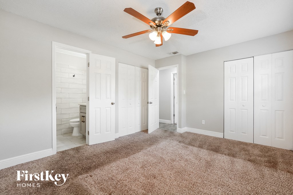 a master bedroom with carpet and a ceiling fan
