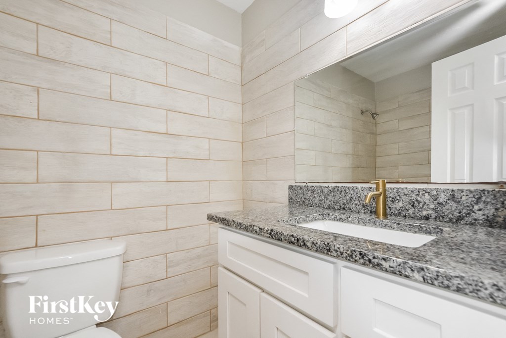 a bathroom with white cabinets and granite counter top and a sink