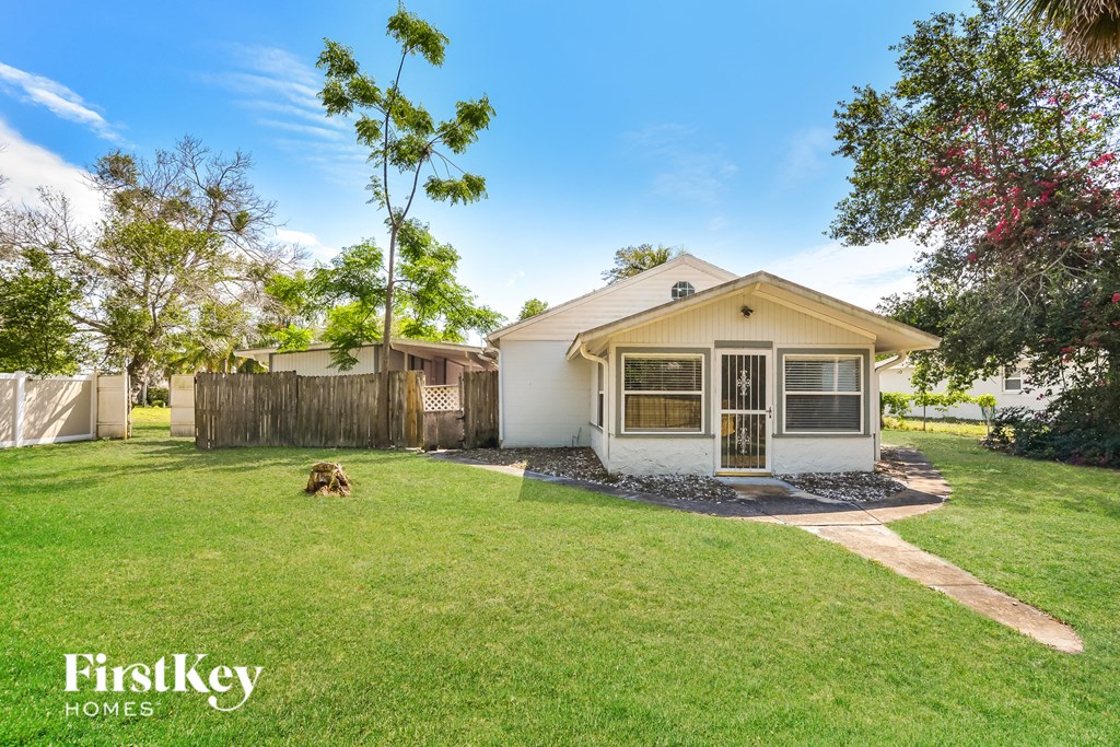 a small white house with a yard and a dog