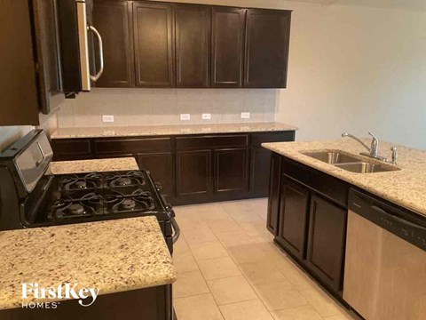A kitchen with dark brown cabinets and granite countertops.