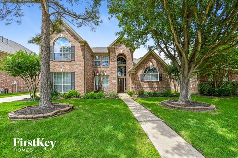 front view of a brick house with trees and grass