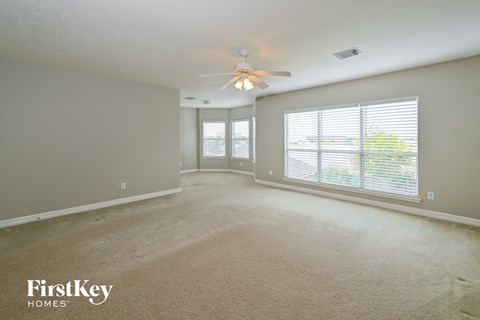 an empty living room with a ceiling fan and a large window