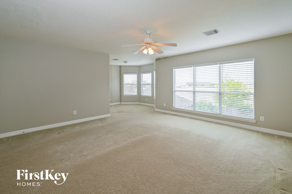 an empty living room with a ceiling fan and a large window