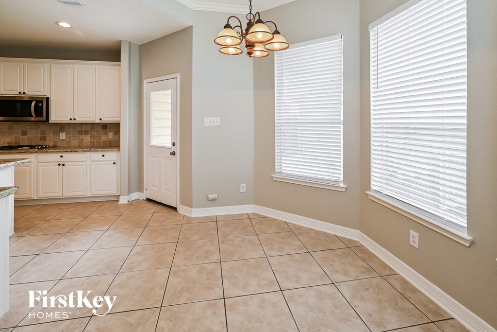a kitchen with white cabinets and a large tiled floor