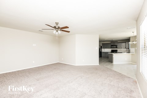 A spacious room with a ceiling fan and a carpeted floor.